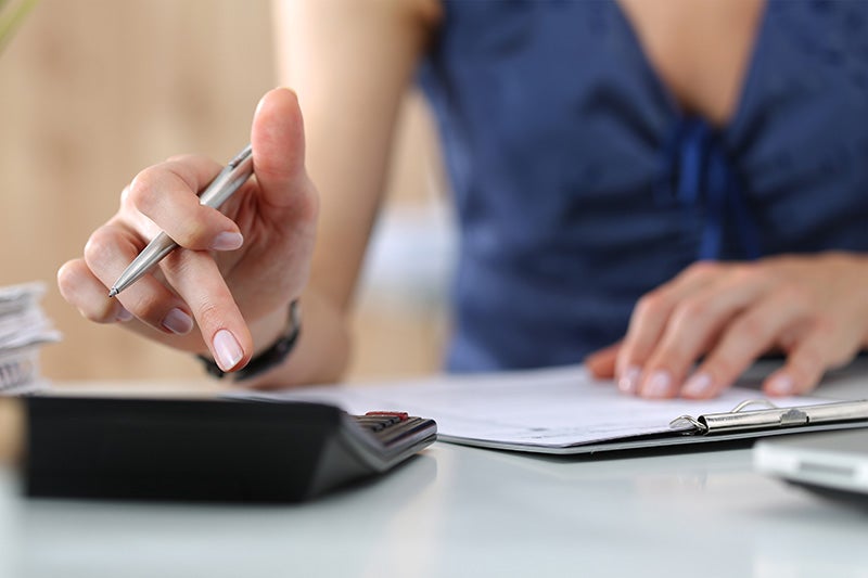 Woman using calculator on desk with paperwork