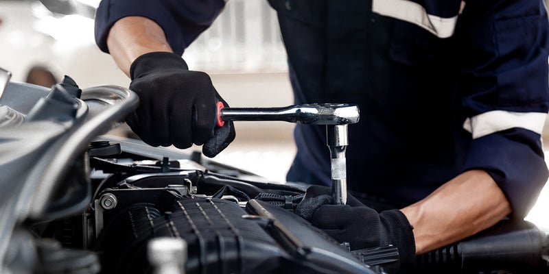 Mechanic using ratchet to work on truck engine