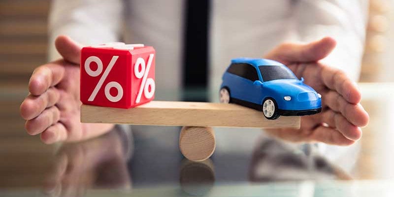 A wooden scale balancing car on one side and dice with percentage symbol on other