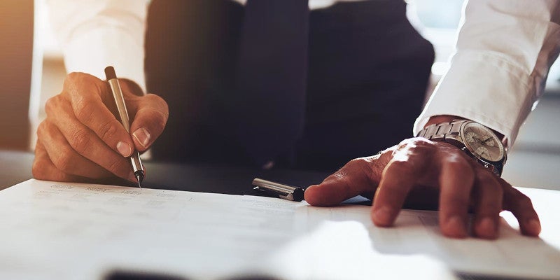 Man standing over desk with lots of paperwork