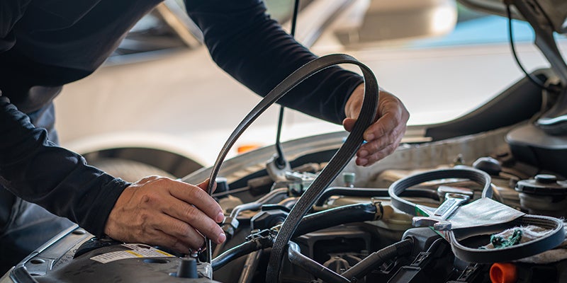 Mechanic changing a belt in a car engine